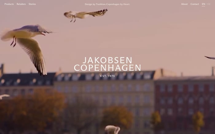 Jakobsen Copenhagen hero: seagulls over city buildings, centered JAKOBSEN COPENHAGEN EST. 1975, and top nav.